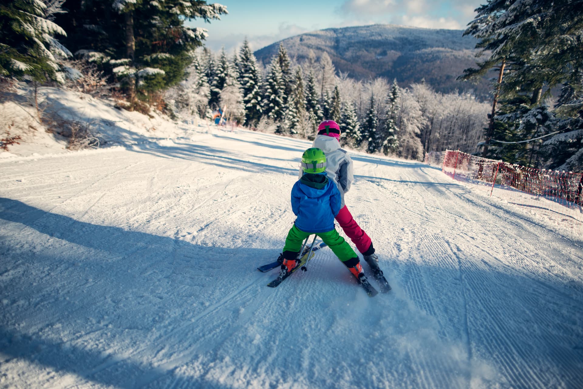Brother and sister skiing together down ski slope